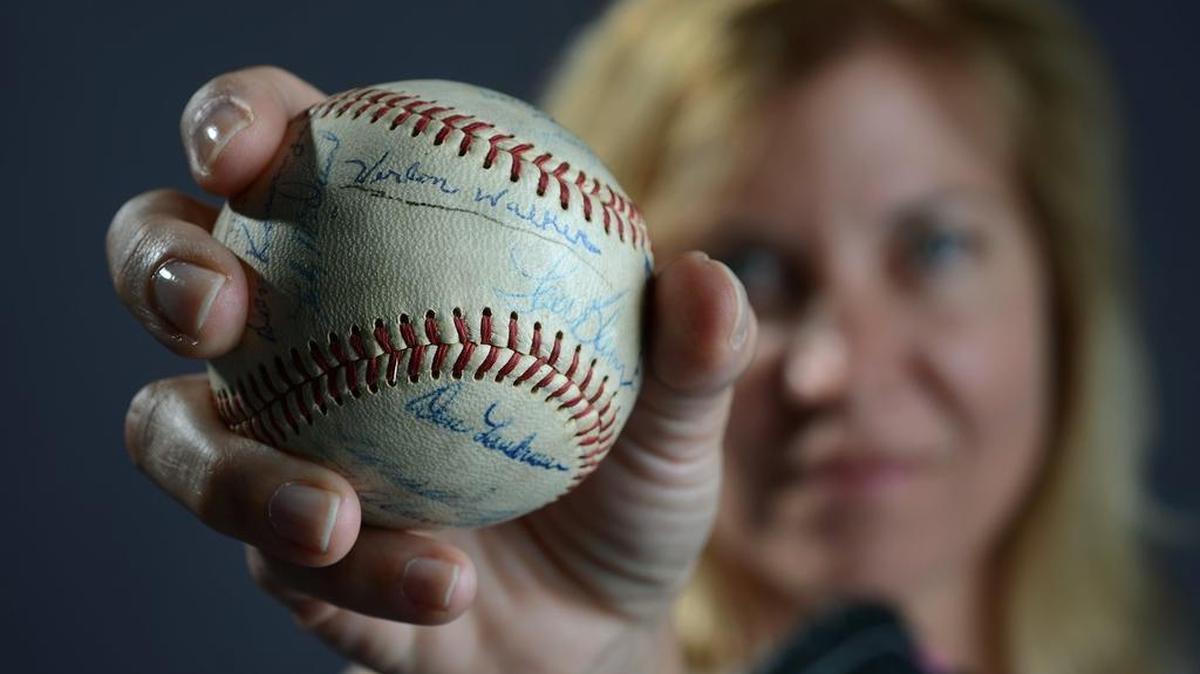 
Charlotte woman Leigh Ann Walker Young was on a quest for four years trying to find a recording of her father Verlon Walker's voice. When she was almost 3, he died of leukemia. Here, Young holds a baseball signed by players on the Chicago Cubs and her father. From Lenoir, Walker was a major-league assistant coach for the Chicago Cubs from 1961-71. He died of leukemia at age 42 in 1971. Walker Young, who posed for this portrait in 2014, found a recording recently courtesy of her mother. 

