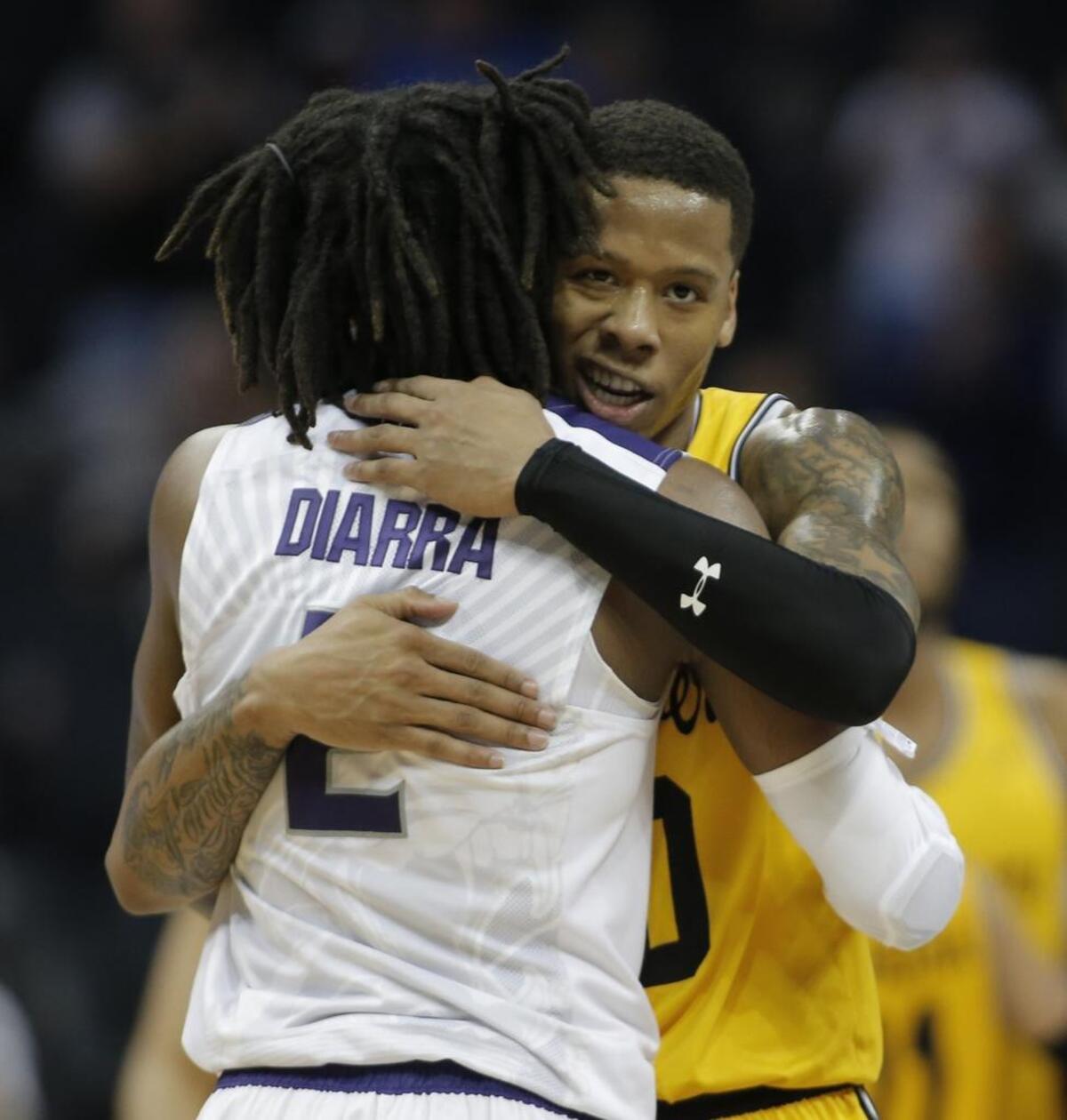 UMBC’s Jairus Lyles, back, hugs Kansas State's Cartier Diarra (2) in the final moments Sunday of Kansas State’s 50-43 win over the Retrievers.