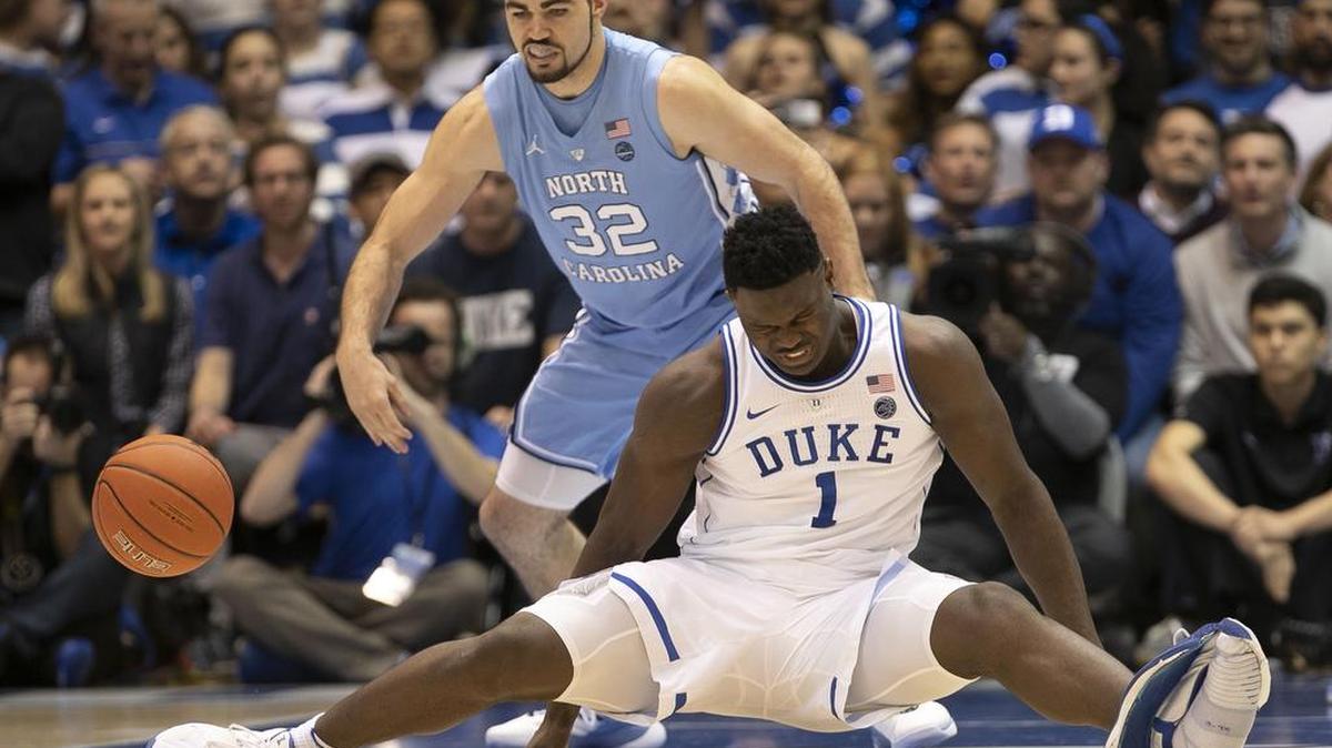 Duke’s Zion Williamson (1) falls to the court Wednesday on the first possession of the game, blowing out his left shoe and injuring his right knee. Luke Maye (32) led UNC to an 88-72 win over No. 1 Duke in Williamson’s absence.