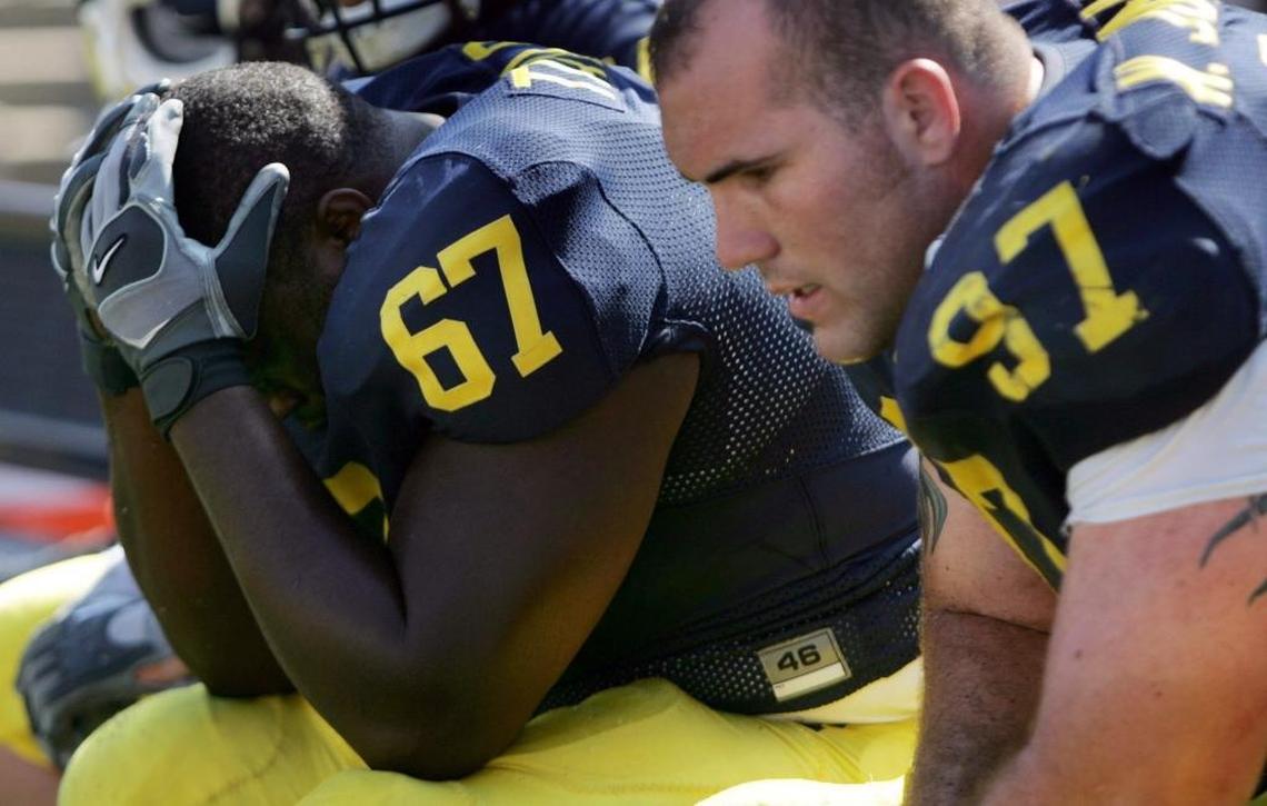 Dejected Michigan defensive tackle Taylor Terrance (67) holds his head in his hands as teammate defensive tackle Will Johnson (97) looks on during Appalachian State’s 34-32 upset win.