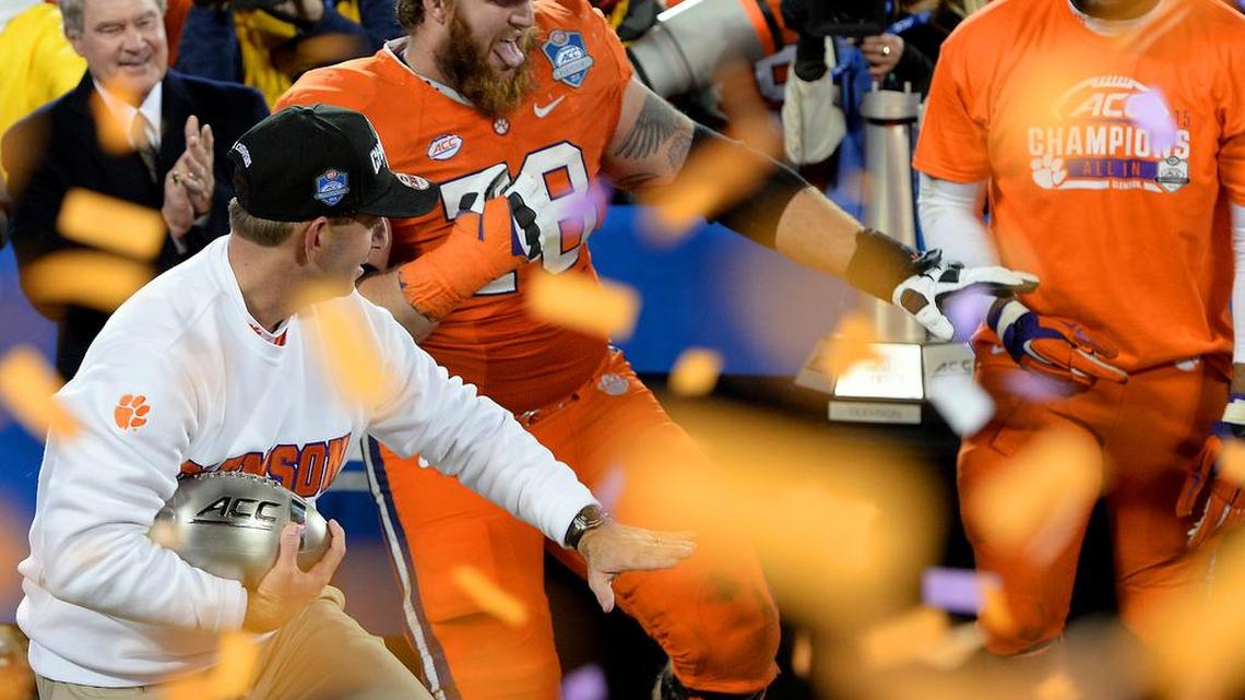 Clemson Tiger head football coach Dabo Swinney, left, and offensive guard Eric Mac Lain strike the Heisman pose as they celebrate the team's 45-37 victory over UNC in the 2015 Dr Pepper ACC Football Championship game at Bank of America Stadium in Charlotte on Saturday.