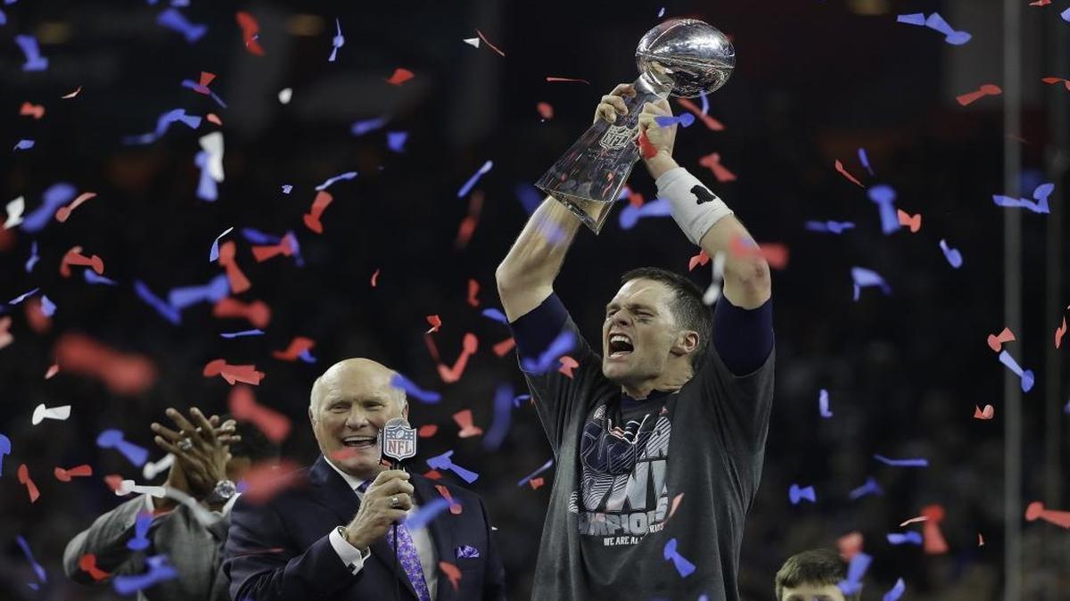 New England Patriots quarterback Tom Brady, right, celebrates with the Vince Lombardi Trophy next to broadcaster Terry Bradshaw after the overtime win against the Atlanta Falcons in Super Bowl 51.
