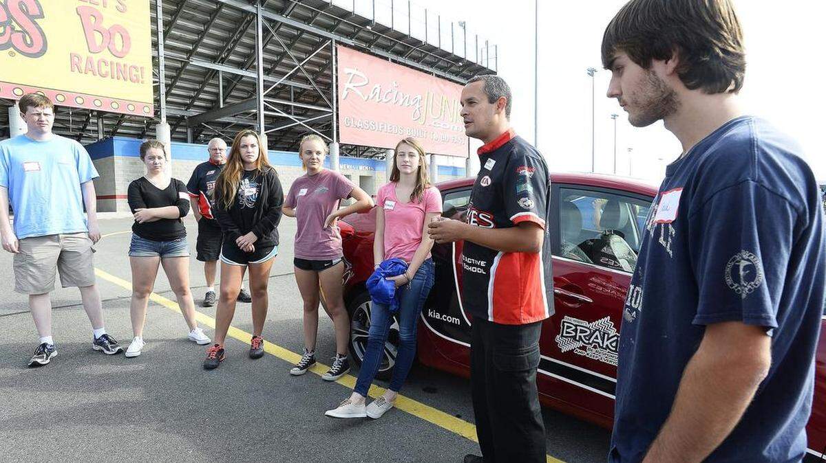 
BRAKES driving instructor Ricordo Rodriguez, second from right, talks to teens before they get into their cars to drive the slalom course during the BRAKES driving school held at zMAX Dragway in Concord. 
