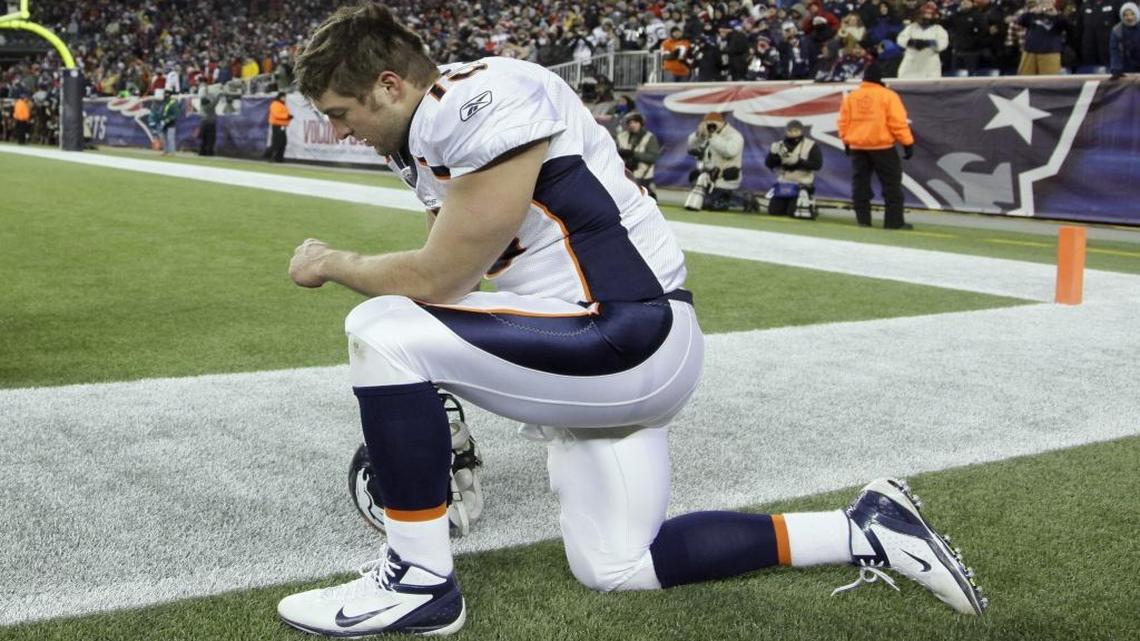 Denver Broncos quarterback Tim Tebow kneels on the sidelines before an NFL divisional playoff football game against the New England Patriots on Jan. 14, 2012, in Foxborough, Mass.