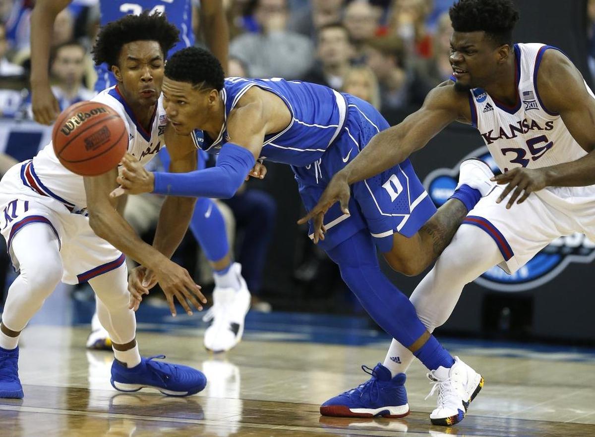 Duke’s Trevon Duval (1) passes the ball under pressure from Kansas’ Devonte’ Graham (4) and Udoka Azubuike (35) during the second half of Sunday’s Kansas’ 85-81 overtime win against Duke in the Midwest Regional Final in Omaha, Neb.