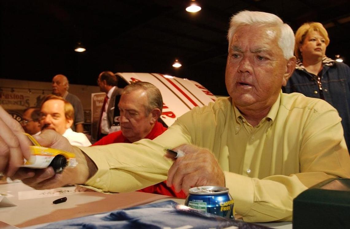 Legendary NASCAR driver Junior Johnson (right) was among the drivers that Tom Higgins (center, behind Johnson’s arm) introduced to retired Observer columnist Tom Sorensen. Above, Johnson and Higgins sign autographs for fans and to help promote the Stocks for Tots Foundation.