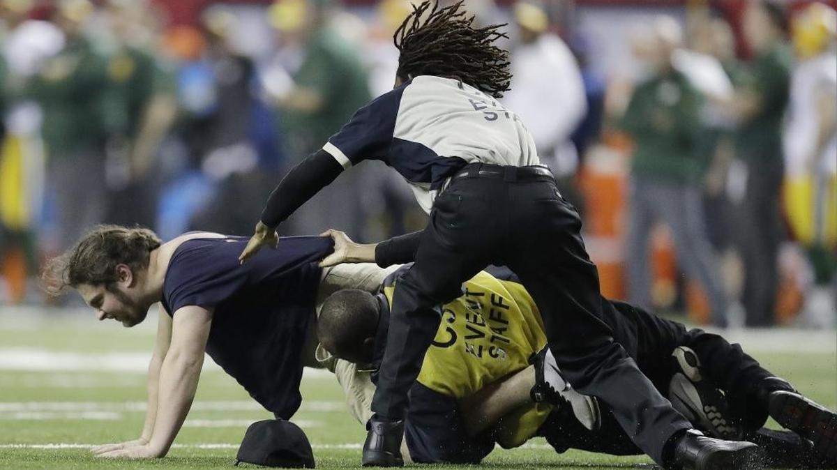Security officials tackle a fan who ran on the field during the second half of the NFC Championship Game between the Green Bay Packers and the Atlanta Falcons on Sunday. Here’s betting they didn’t take him back to his mother’s basement.