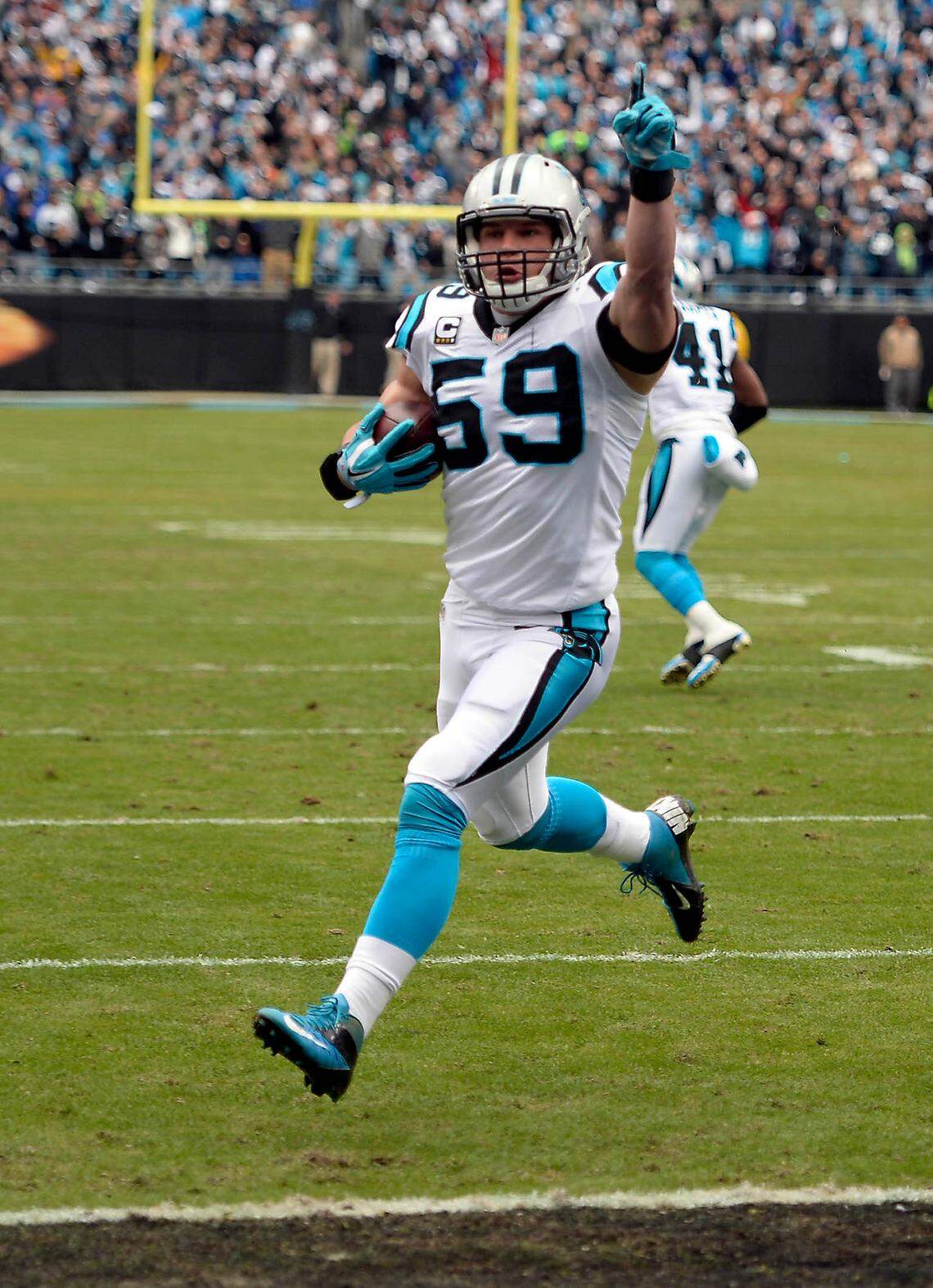 Carolina Panthers linebacker Luke Kuechly (59) celebrates as he returns an interception for a touchdown against the Seattle Seahawks and quarterback Russell Wilson in a playoff game Jan. 17, 2016. Kuechly says the pass rush of defensive tackle Kawann Short made the play happen, and the result was one of the loudest roars in Bank of America Stadium history.