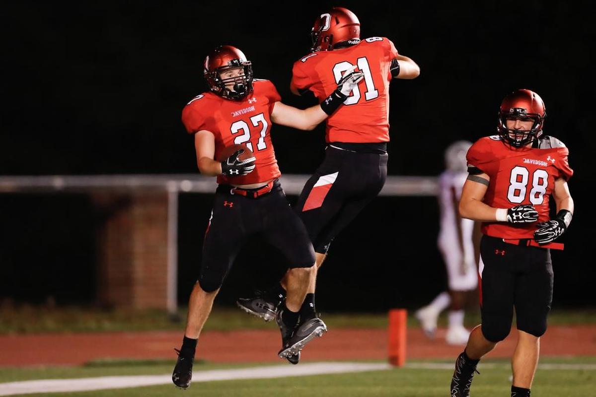 Davidson freshman running back Coy Williams (27), after scoring one of his two fourth-quarter touchdowns, celebrates with teammates Nick Snyder (81) and Tyler Soloman (88) in the Wildcats’ 91-61 nonconference football victory against Guilford on Thursday.