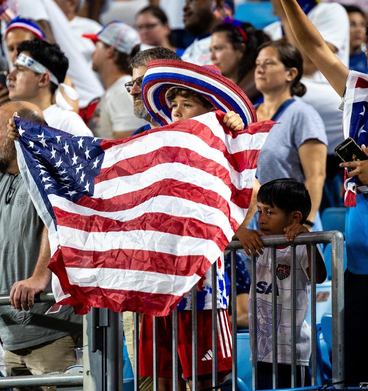 A young fan wears a patriotic sombrero and waves a flag after Team USA beat Trinidad and Tobago 6-0 in a 2023 match at Bank of America Stadium.