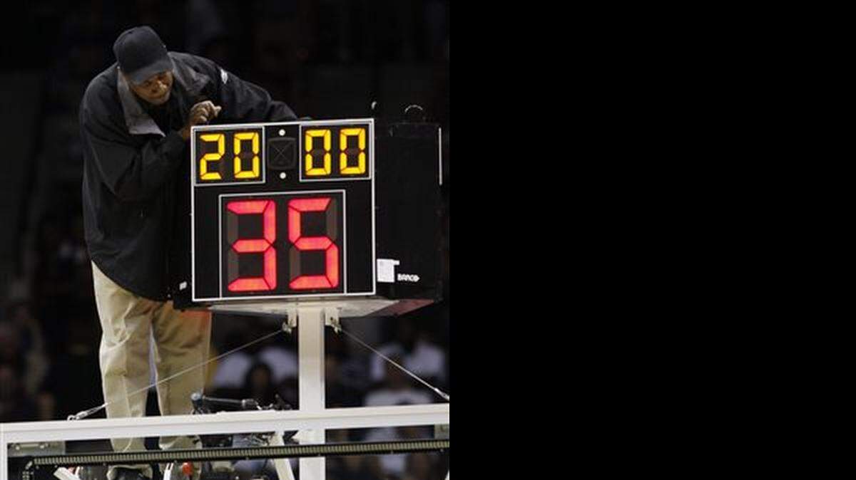 
In this March 19, 2010, file photo, a technician adjusts a shot clock after it malfunctioned and delayed the start of the California against Louisville NCAA first-round college basketball game in Jacksonville, Fla. 
