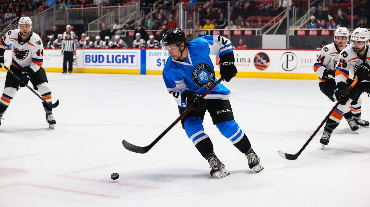 Dennis Cesana, sporting a Charlotte FC uniform, controls the puck during a Charlotte Checkers home game on Dec. 3, 2022.