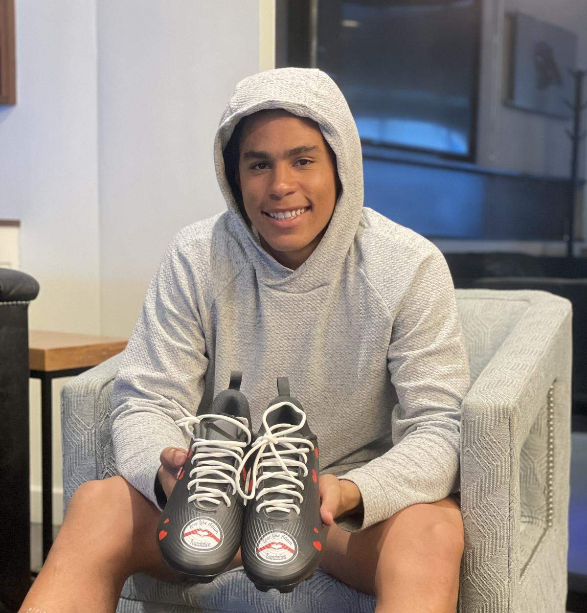 Carolina Panthers wide receiver Jalen Coker poses with his customized cleats that represent the “Love Like Adam Foundation.” Coker has been a staunch supporter of the organization that is meant to honor his childhood friend since its inception in 2021.